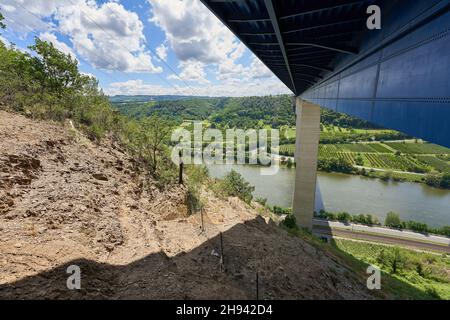 Pont de la vallée de la Moselle par le dessous, construction en acier bleu soutenue par de grands piliers gris, ciel bleu et arbres verts.Allemagne. Banque D'Images