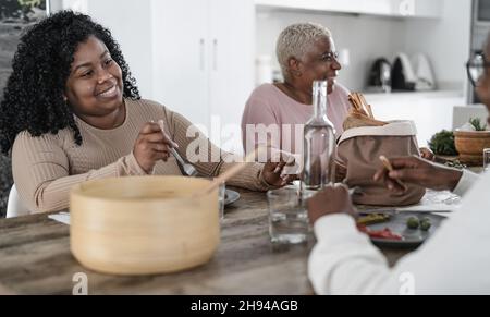 Bonne famille afro latine manger un déjeuner sain avec des légumes frais À la maison - concept de l'unité de la nourriture et des parents Banque D'Images