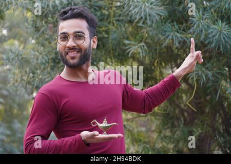 Un homme portant des lunettes et la lampe d'Aladin dans sa main Banque D'Images