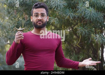 Un homme portant des lunettes et la lampe d'Aladin dans sa main Banque D'Images