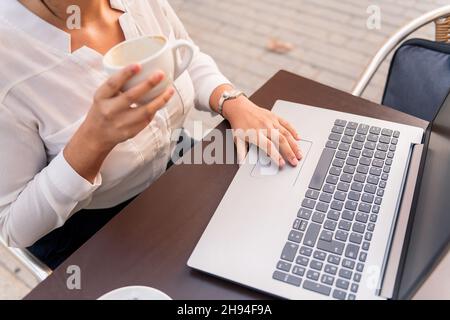 femme d'affaires méconnue travaillant avec son ordinateur portable tout en buvant un café sur une terrasse, concept d'entrepreneur numérique et de style de vie urbain Banque D'Images