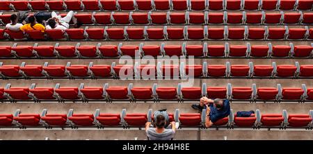 les spectateurs du stade assis dans des sièges rouges regardent le match Banque D'Images