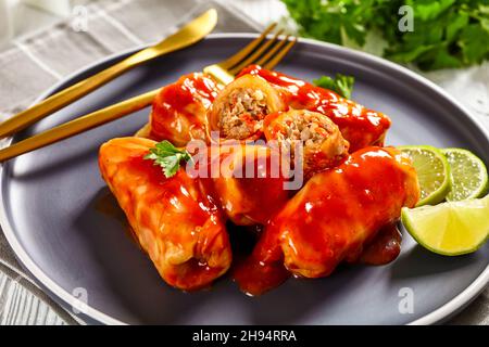 Les golubtsi ukrainiens sont des rouleaux de chou farcis avec de la viande hachée et du riz, cuits dans une sauce à base de tomate, servis sur une assiette sur une table en bois, gros plan Banque D'Images