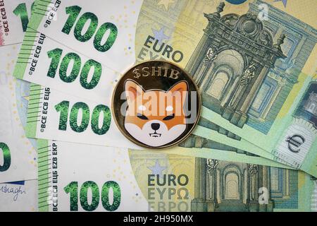 Pièce physique Shiba Inu qui s'élève au-dessus des factures de 100 euros. Banque D'Images