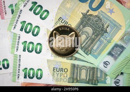 Pièce physique Shiba Inu qui s'élève au-dessus des factures de 100 euros. Banque D'Images