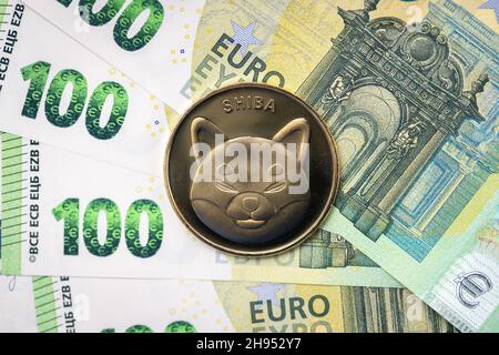 Pièce physique Shiba Inu qui s'élève au-dessus des factures de 100 euros. Banque D'Images