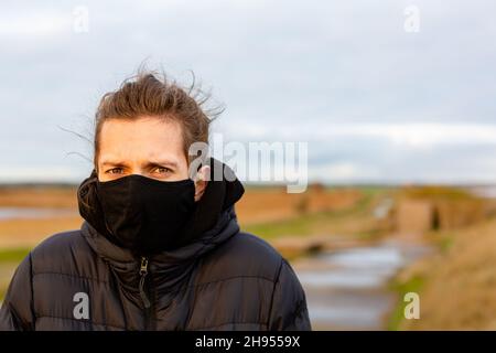 Un jeune homme portant un masque noir lavable pendant la pandémie du virus corona Covid-19 Banque D'Images