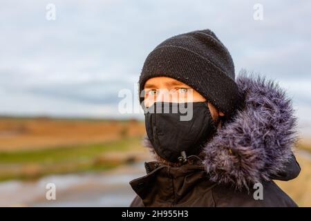 Un jeune homme portant un masque noir lavable pendant la pandémie du virus corona Covid-19 Banque D'Images