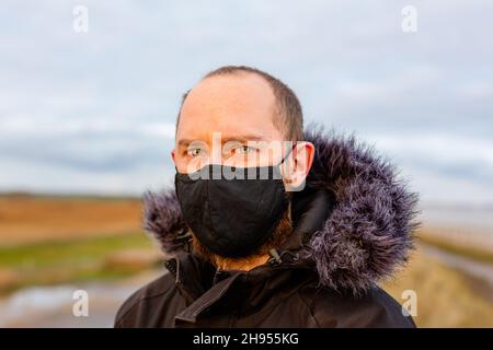 Un jeune homme portant un masque noir lavable pendant la pandémie du virus corona Covid-19 Banque D'Images