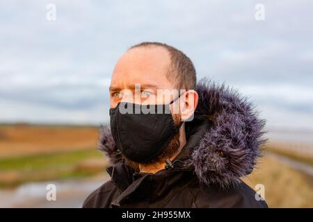 Un jeune homme portant un masque noir lavable pendant la pandémie du virus corona Covid-19 Banque D'Images