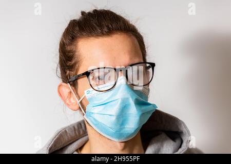 Jeune homme avec des lunettes brumeuses causées par le port d'un masque jetable. Mesure de protection en cas de pandémie de coronavirus Banque D'Images