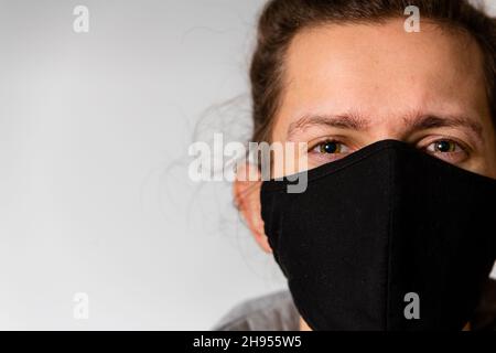 Un jeune homme portant un masque noir lavable pendant la pandémie du virus corona Covid-19 Banque D'Images