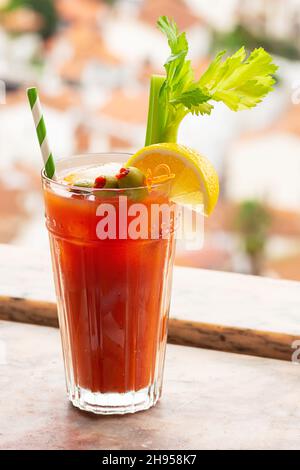 Bloody Mary cocktail avec garniture d'olives, citron et céleri sur le rebord de la fenêtre en marbre dans le village portugais européen Banque D'Images