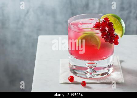 Cocktail Red Currant Caipirinha avec garniture citron et baies sur comptoir en marbre minimaliste Banque D'Images