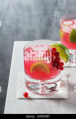 Cocktail Red Currant Caipirinha avec garniture citron et baies sur comptoir en marbre minimaliste Banque D'Images