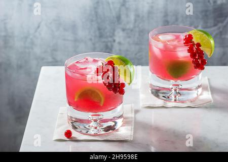 Cocktail Red Currant Caipirinha avec garniture citron et baies sur comptoir en marbre minimaliste Banque D'Images