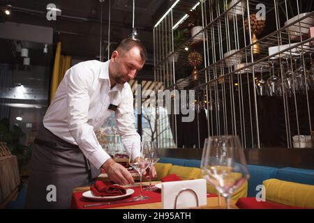 Photo sous angle d'un serveur professionnel préparant des tables pour les clients du restaurant Banque D'Images