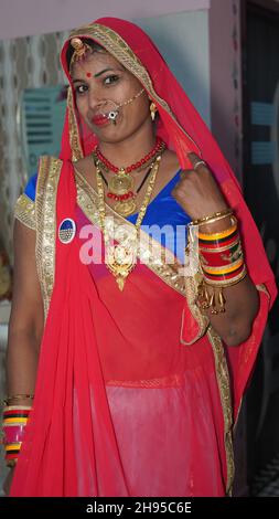 Rajasthani jeune femme en costume rouge avec des bijoux traditionnels et des bracelets colorés. Banque D'Images