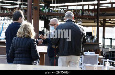 Palma, Espagne.04e décembre 2021.Les clients montrent à Artur, un serveur au Bar Pesquero, leur "passeport Covid".Pour visiter des bars, des restaurants et d'autres établissements d'une capacité de plus de 50 personnes, un certificat de vaccination ou de convalescence ou un résultat de test négatif doit être présenté depuis 04.12.2021.Credit: Clara Margais/dpa/Alay Live News Banque D'Images