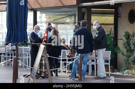 Palma, Espagne.04e décembre 2021.Les clients montrent Artur, serveur au Bar Pesquero, leur certificat numérique Covid.Pour visiter des bars, des restaurants et d'autres établissements d'une capacité de plus de 50 personnes, un certificat de vaccination ou de convalescence ou un résultat de test négatif doit être présenté depuis 04.12.2021.Credit: Clara Margais/dpa/Alay Live News Banque D'Images