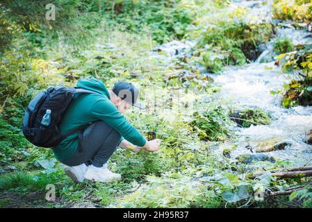 Un jeune touriste mâle prend des photos sur un smartphone dans une forêt.Tourisme, mode de vie actif Banque D'Images