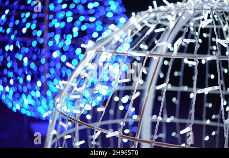 Décoration extérieure de Noël - chaînes de lumière LED bleues et blanches disposées sur de grandes boules - gros plan détail abstrait, seulement peu de câbles et d'ampoule en foyer Banque D'Images