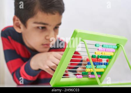 Un écolier fait des mathématiques mentales.Mathématiques mentales.garçon multiracial de 8 ans occupé avec l'arithmétique mentale.Garçon dans les cours de mathématiques.Faire des devoirs, faire des maths à Banque D'Images