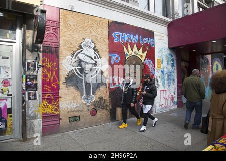 Les gens marchent le long de la 125e rue à Harlem par un portrait d'un Biggie couronné peint sur un mur non loin du théâtre Apollo.New York. Banque D'Images