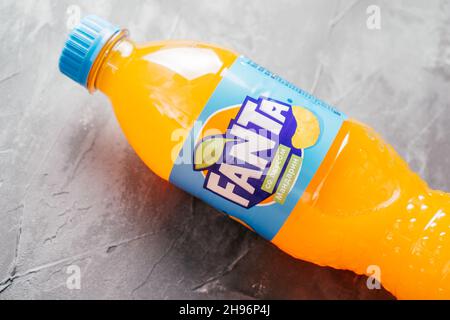 La bouteille en plastique transparent de Fanta se trouve sur une surface en béton gris.Bouteille avec boisson à l'orange et étiquette bleue au goût de mandarine en russe Banque D'Images