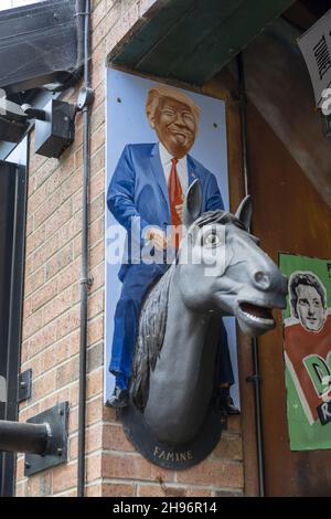 BELFAST, ROYAUME-UNI - 02 novembre 2021 : un cliché vertical d'une caricature de Donald Trump sur un cheval artificiel attaché à un mur de briques Banque D'Images
