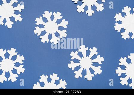 Magnifiques flocons de neige en papier sur fond bleu Banque D'Images