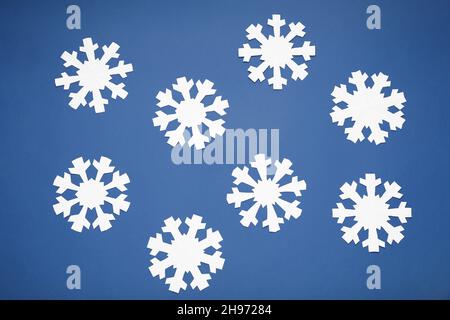 Magnifiques flocons de neige en papier sur fond bleu Banque D'Images