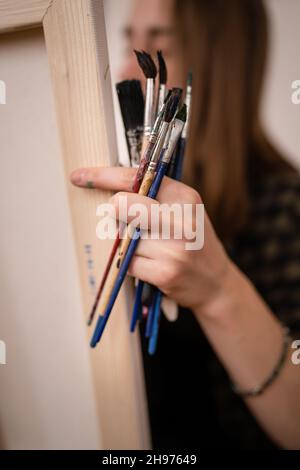 Une jeune femme caucasienne artiste professionnelle ou étudiante peintre amateur peinture à la maison tenant des pinceaux à la main posant avec l'espace de copie c Banque D'Images