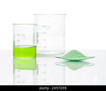 Sulfate ferreux dans le verre de surveillance chimique placer à côté du liquide sulfate de fer (II) dans le bécher.Gros plan sur l'ingrédient chimique sur la table de laboratoire blanche.Côté Banque D'Images