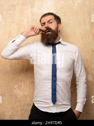 Portrait d'un bel homme barbu fumant un cigare. Banque D'Images