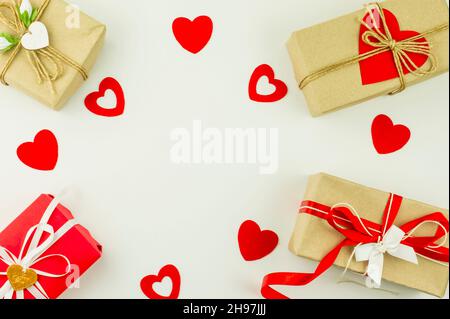 Arrière-plan des fêtes de la Saint-Valentin. Boîtes-cadeaux en papier artisanal, décorées de coeurs colorés et de coeurs rouges sur fond blanc. Vue du dessus. flat Lay Banque D'Images