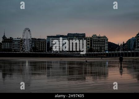 À Donostia, un homme marche le long de la plage de la Concha pendant la marée basse tôt le matin. Banque D'Images