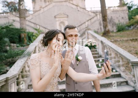 La mariée et le marié prennent un selfie avec des anneaux sur leurs doigts Banque D'Images