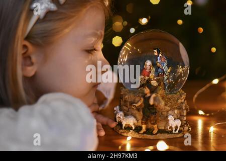 Fille regardant une boule de verre avec une scène de la naissance de Jésus-Christ Banque D'Images