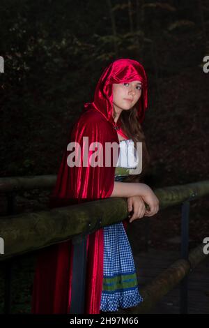 Little Red Riding Hood debout sur un pont sur un sentier de randonnée dans la Forêt-Noire de l'Allemagne le jour de l'automne. Banque D'Images