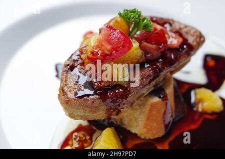 Foie gras poêlé et pain de baguette avec sauce noire sur la plaque blanche vue de dessus Banque D'Images