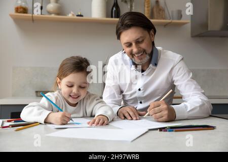 Bonne petite fille dessin avec le père à la maison. Banque D'Images