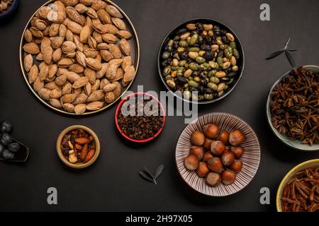 Edamame aux haricots secs, amandes décortiquées, fruits secs et noisettes avec feuilles d'olive sur fond noir Banque D'Images