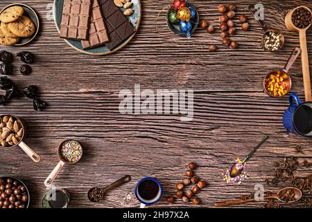 Durée de vie des chocolats, noisettes salées grillées et amandes, jus d'orange, table en bois et biscuits au chocolat sur fond de planches en bois Banque D'Images