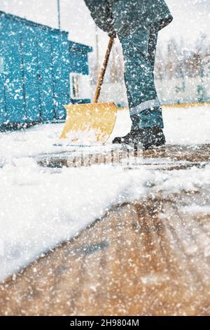 Le concierge nettoie la zone de neige avec une pelle en bois.Nettoyage des rues après les chutes de neige et le blizzard.Arrière-plan. Banque D'Images