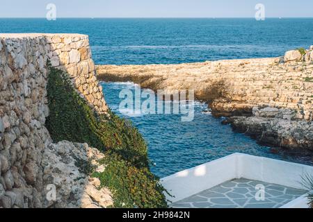 Paysage de mer méditerranéen avec falaise rocheuse, belle mer bleue, végétation, murs en pierre et constructions en maçonnerie Banque D'Images