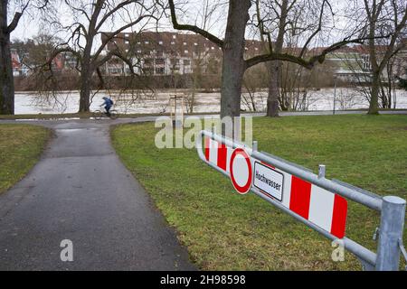 Panneau avant un pré vert disant: Inondation ( germann: Hochwasser).La rivière Neckar est en arrière-plan.Le cycliste passe au-delà.Allemagne, Bade-Wurtemberg Banque D'Images