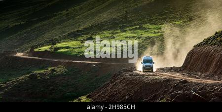 Dans les montagnes de l'Atlas au Maroc.Une fourgonnette 4x4 soulève un nuage de poussière sur la route de terre qui monte vers le Tizi N'Highist dans la vallée de l'ait Boulli Banque D'Images