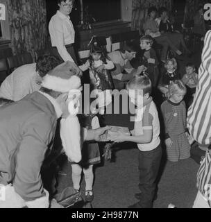 John Laing and son Limited, page Street, Mill Hill, Barnett, Londres,13/12/1986.Un jeune garçon reçoit un cadeau du Père Noël lors d'une fête de Noël pour enfants dans les bureaux de Laing's Mill Hill.Cette fête de Noël était destinée aux enfants âgés de quatre à sept ans. Banque D'Images