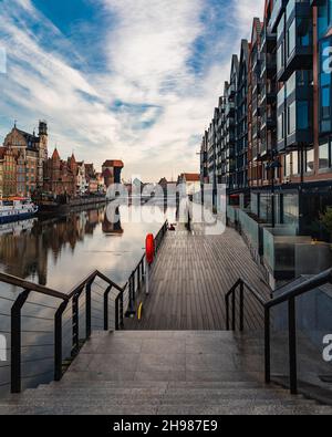 Gdansk, Pologne - octobre 24 2020 : longue plate-forme en bois à côté du long passage des bâtiments à côté de la rivière avec réflexions des bâtiments Banque D'Images